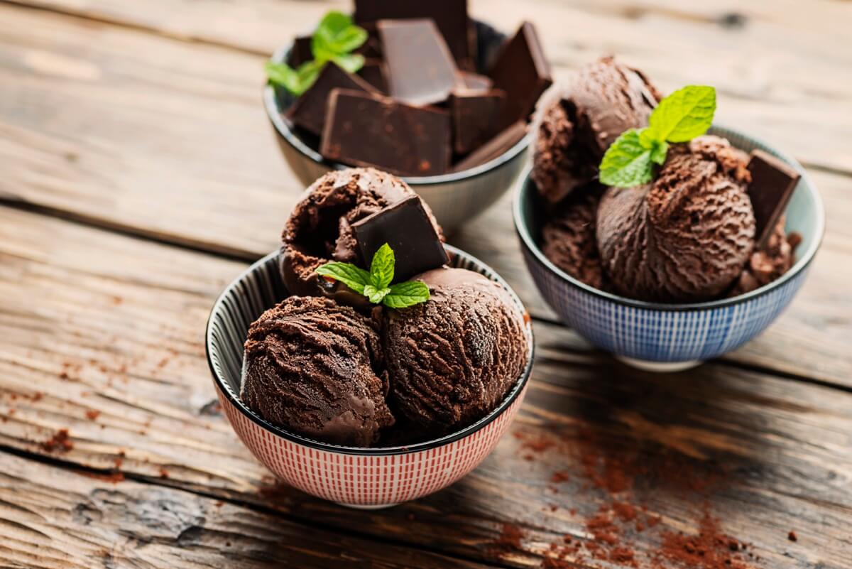 Three bowls of chocolate ice cream on a wooden table