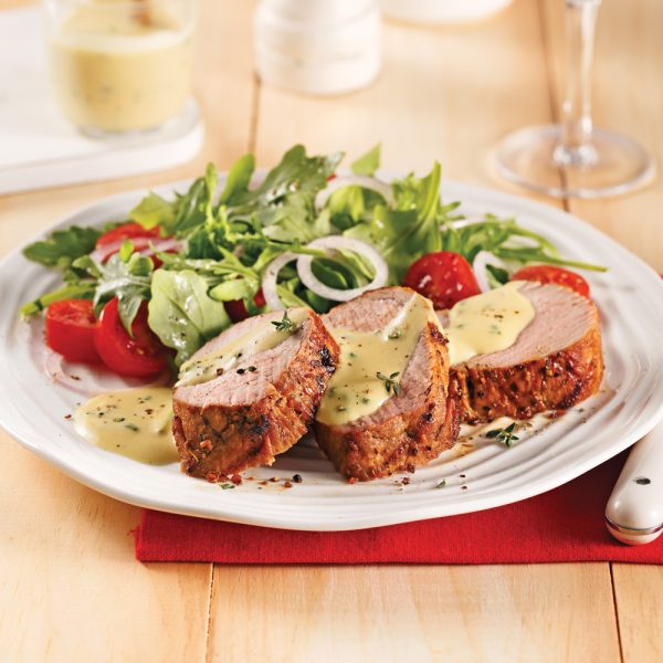 Plate of 3 slices of pork tenderloin topped with mustard sauce accompanied by a garden salad