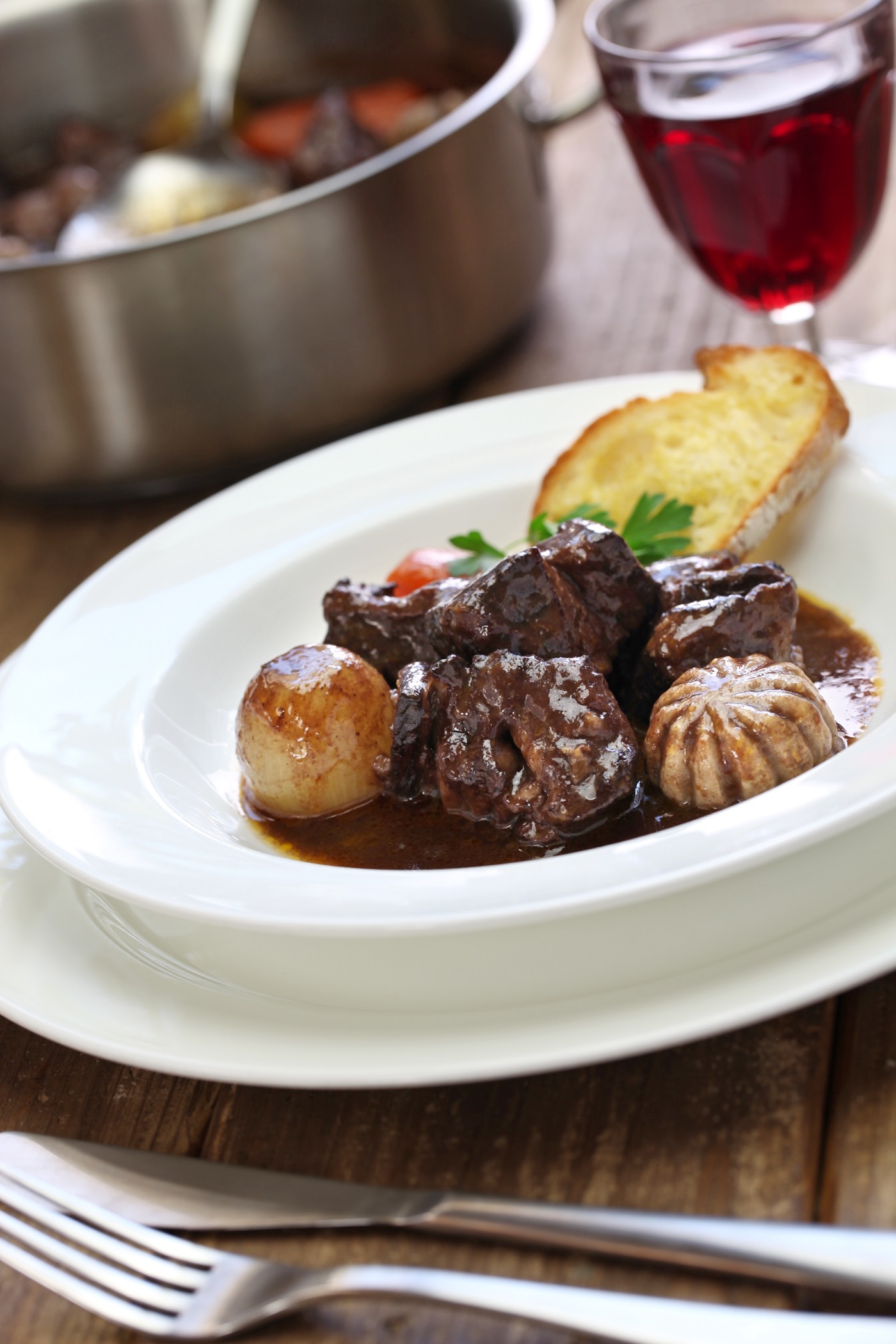 A stew of beef cooked in red wine served with a glass of wine