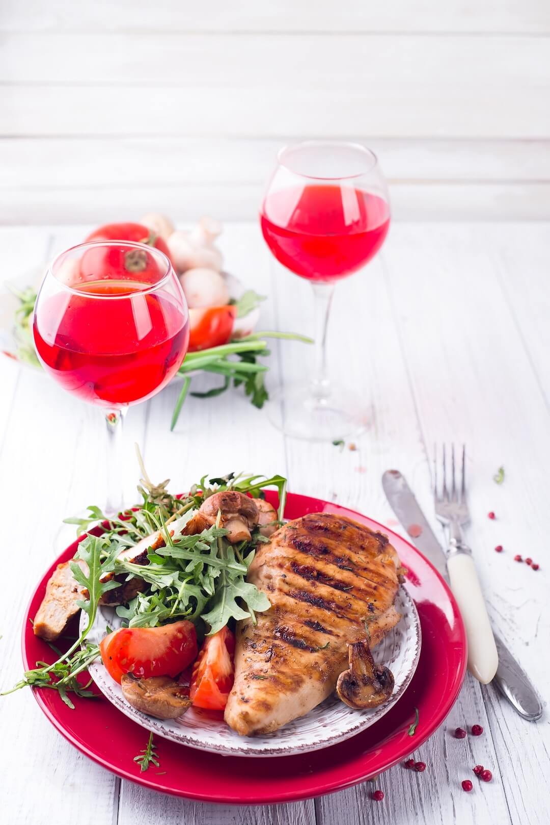 Poitrine de poulet avec roquette et tomates sur une assiette et vin rosé sur une table