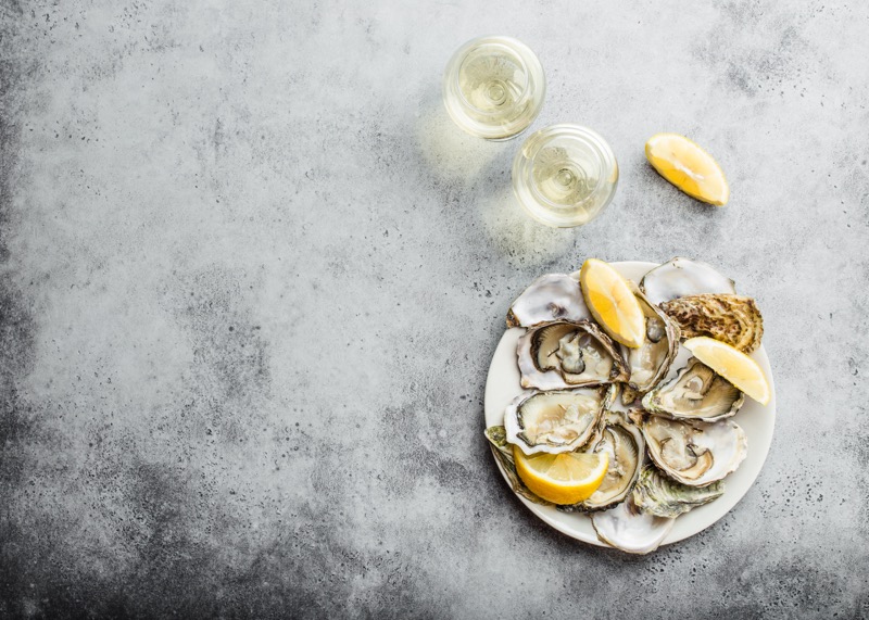 Open fresh oysters with two glasses of white wine on a table