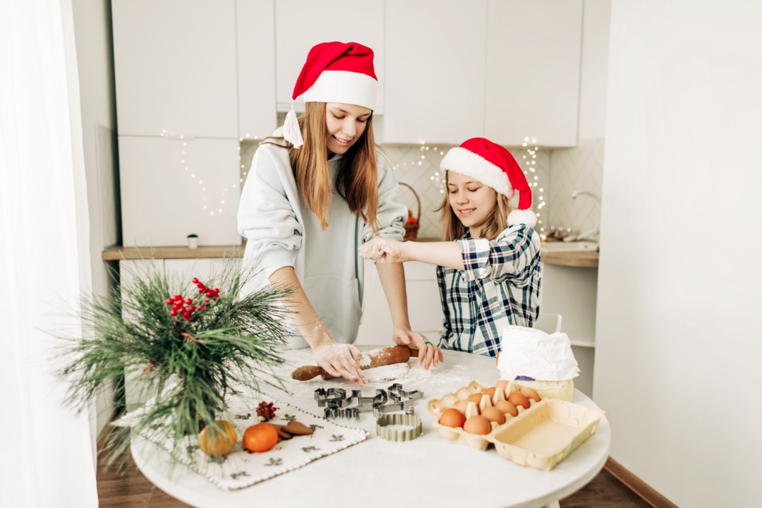 A girl helps her older sister to prepare a Christmas dessert.